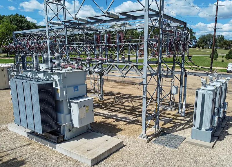 Transformers, insulators, and wiring at an outdoor electrical substation.