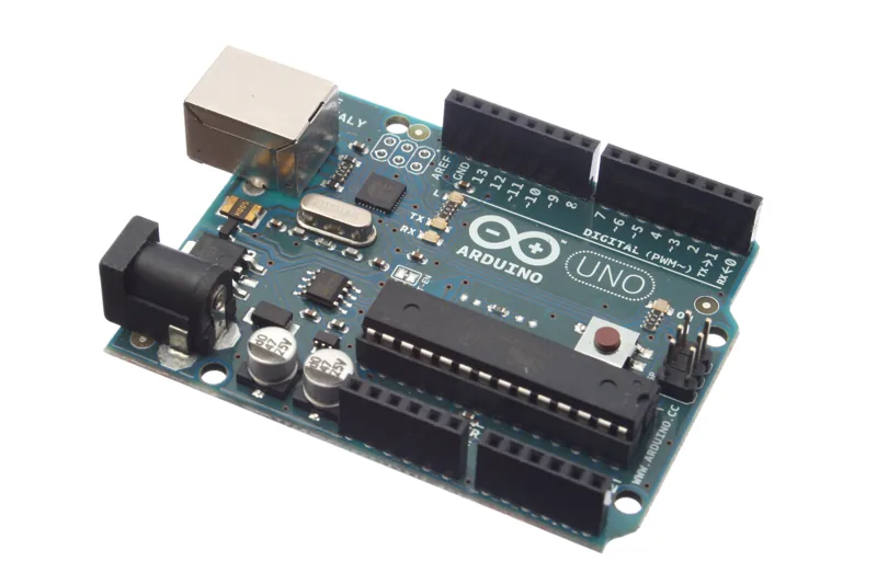 An Arduino Uno microcontroller board photographed from an angle against white.