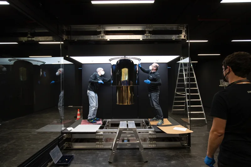 Engineers work beside the gold-colored quantum computing assembly during an IBM Quantum System One installation.