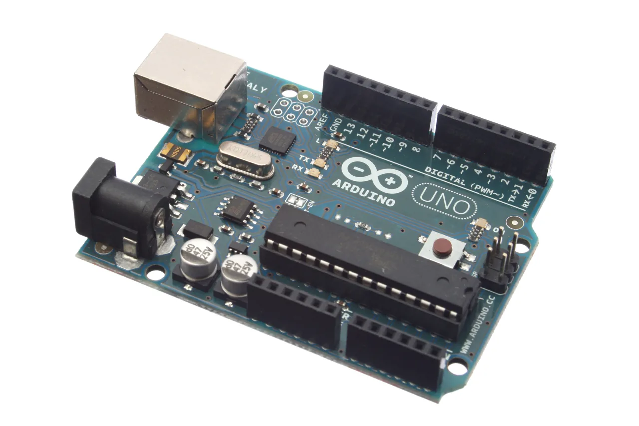 An Arduino Uno microcontroller board photographed from an angle against white.