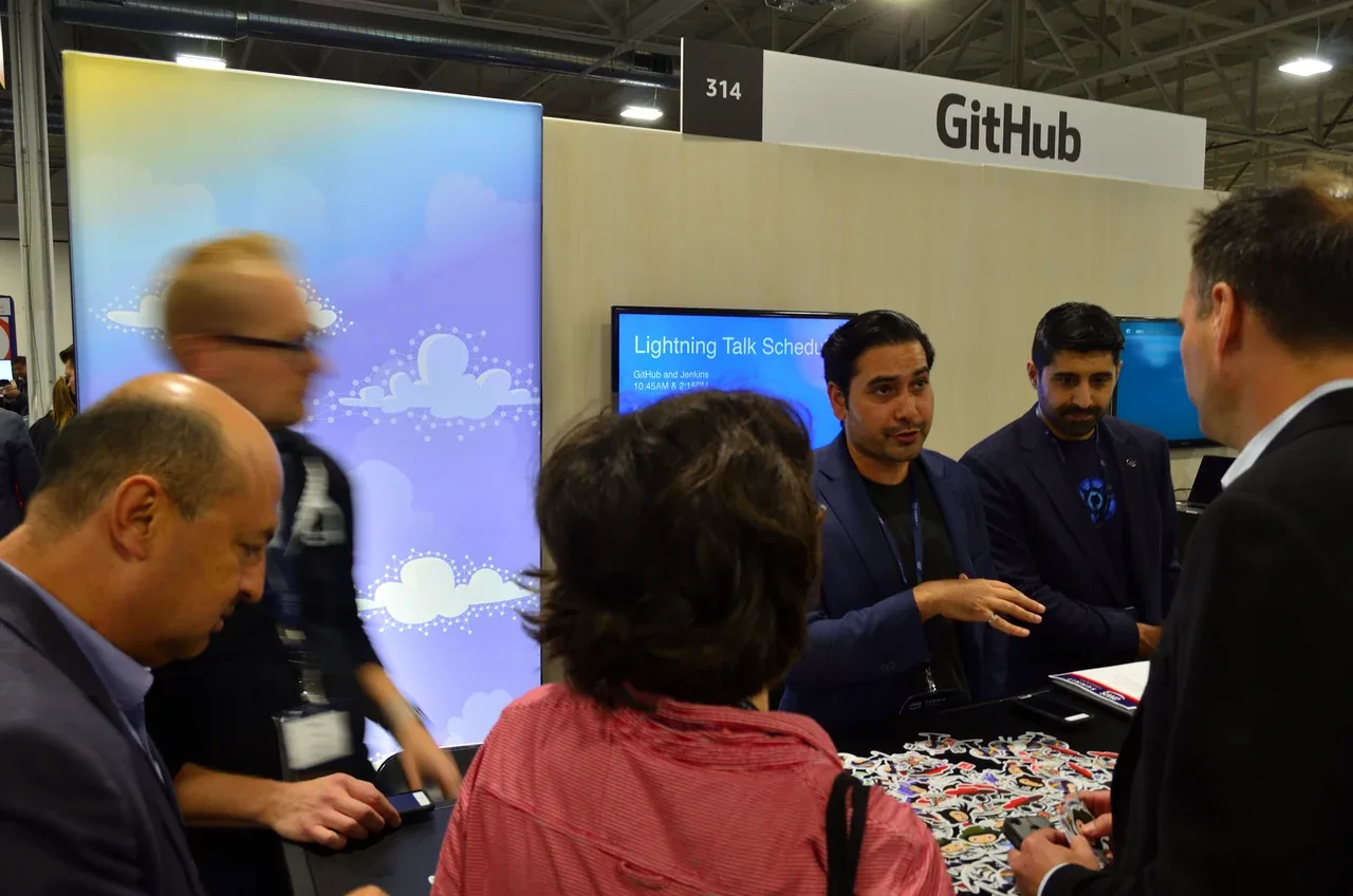 Visitors talk with staff at a GitHub conference booth.